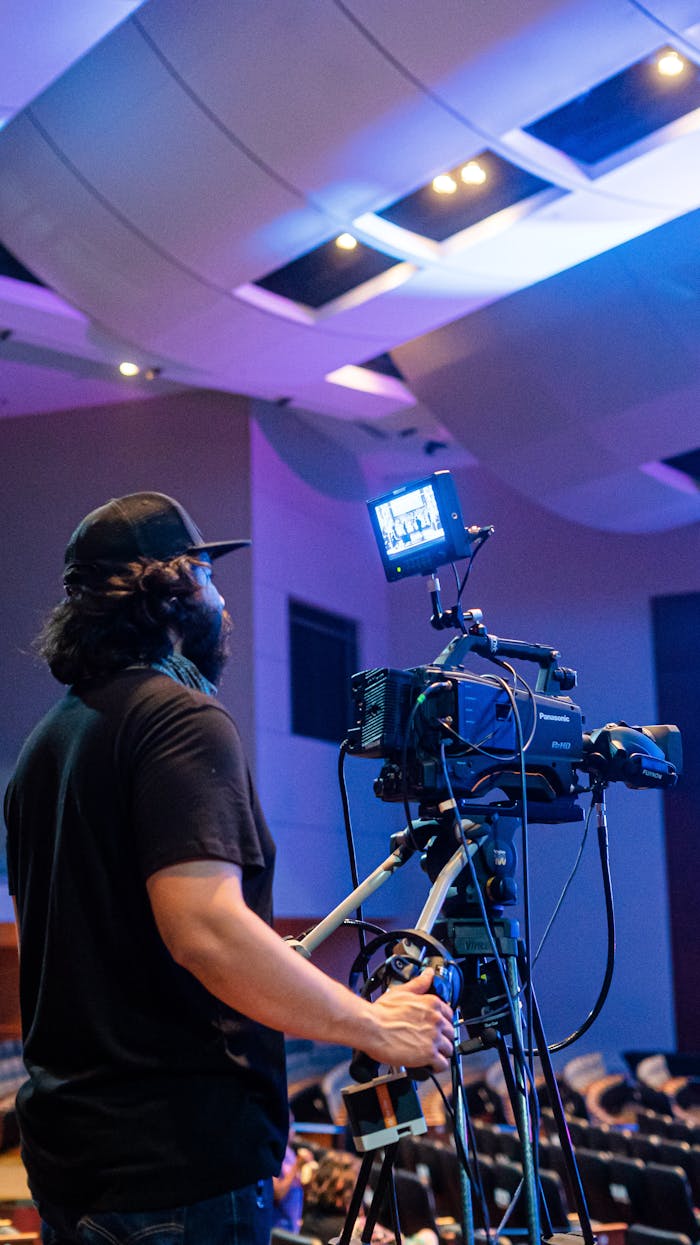 about-01 Back view of bearded camera man recording stage during music performance in illuminated concert hall