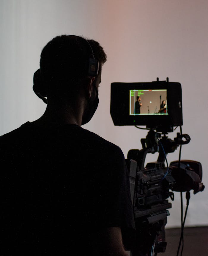 why-choose-us Silhouette of a cameraman operating professional video equipment in a studio setting.
